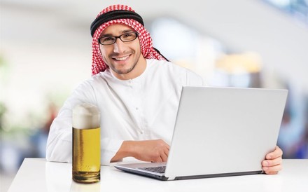 ARaber mit Notebook und einem Glas Bier