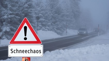 Warnschild "Schneechaos" vor einer Winterlandschaft