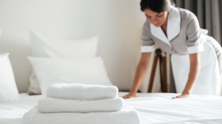 Dunkelhaarige Frau richtet ein Hotelbett her