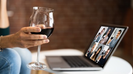 Frau mit Weinglas vor einem Onlineseminar