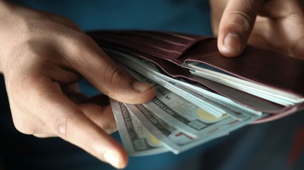 Mann zieht mehrere 100-Dollar-Noten aus der Geldbörse