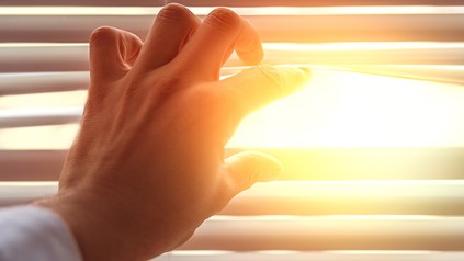 Geöffneter Rolladen, der Sonnenstrahlen hineinlässt.