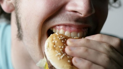 Mann beißt in Burger