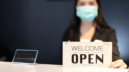 Frau mit Open Schild an Hotelrezeption