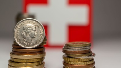 Zwei Stapel Münzen vor einer schweizer Flagge