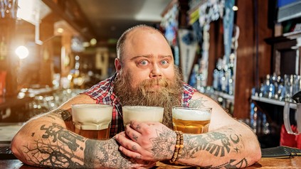 Ein lustiger dicker Mann mit drei Bieren an einer Bar