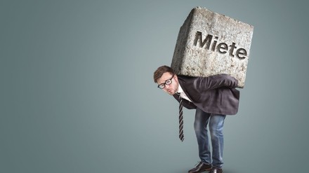 Mann trägt Felsbrocken mit der Aufschrift „Miete“ auf seinem Rücken