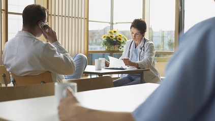 drei Ärzte sitzen in einer Kantine und trinken Kaffee