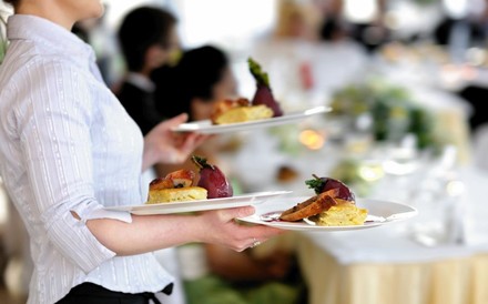 Kellnerin trägt mehrere volle Teller an einen Tisch