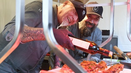 Zwei bärtige Männer marinieren ein paar Steaks auf einem Grill