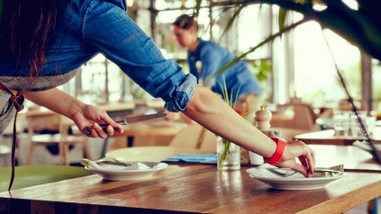 Kellnerin deckt Tisch