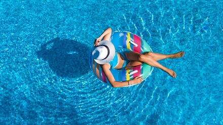 Urlauberin treibt mit Schwimmreifen im Pool