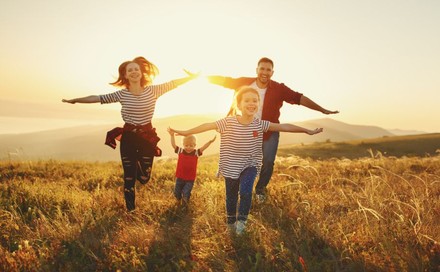 Glückliche Familie läuft im Sonnenuntergang über ein Feld