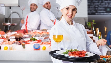 Eine junge Köchin präsentiert Wein und Fisch