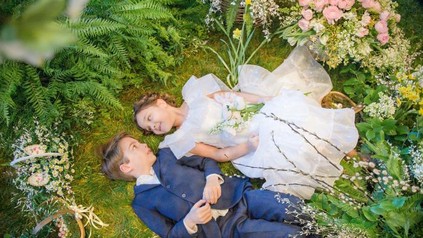 Zwei Kinder liegen glücklich in einem Märchenwald