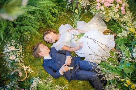 Zwei Kinder liegen glücklich in einem Märchenwald