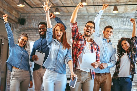 Eine Gruppe junger Leute streckt siegessicher die Arme in die Höhe