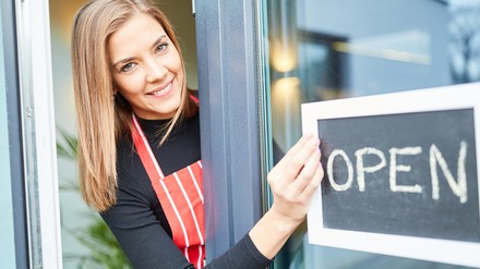 Junge Servicekraft mit Open-Schild