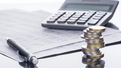 Taschenrechner, Geldmünzen, Kugelschreiber und Liste