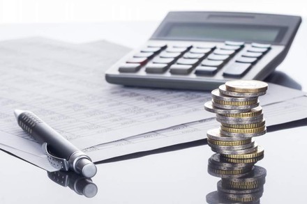 Taschenrechner, Geldmünzen, Kugelschreiber und Liste