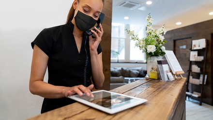 Frau am Empfang mit Telefon und Tablet