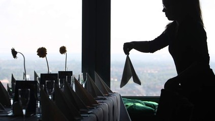 Servicekraft deckt Tisch mit Servietten