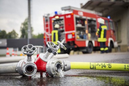 Feuerwehrschlauch mit Feuerwehrwagen im Hintergrund