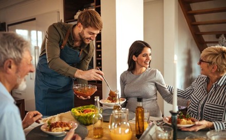 Mann serviert in seiner Wohnung Freunden ein Essen