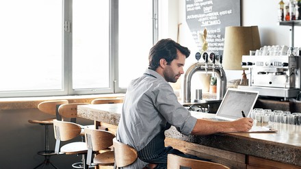Gastronom an der Theke mit Pc, Block und Stift
