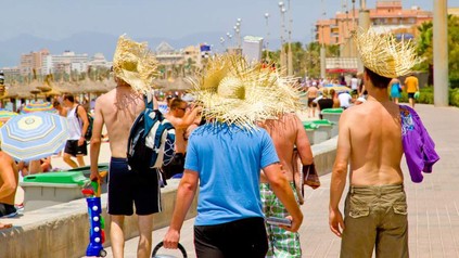 Touristen mit Strohhut an Strand